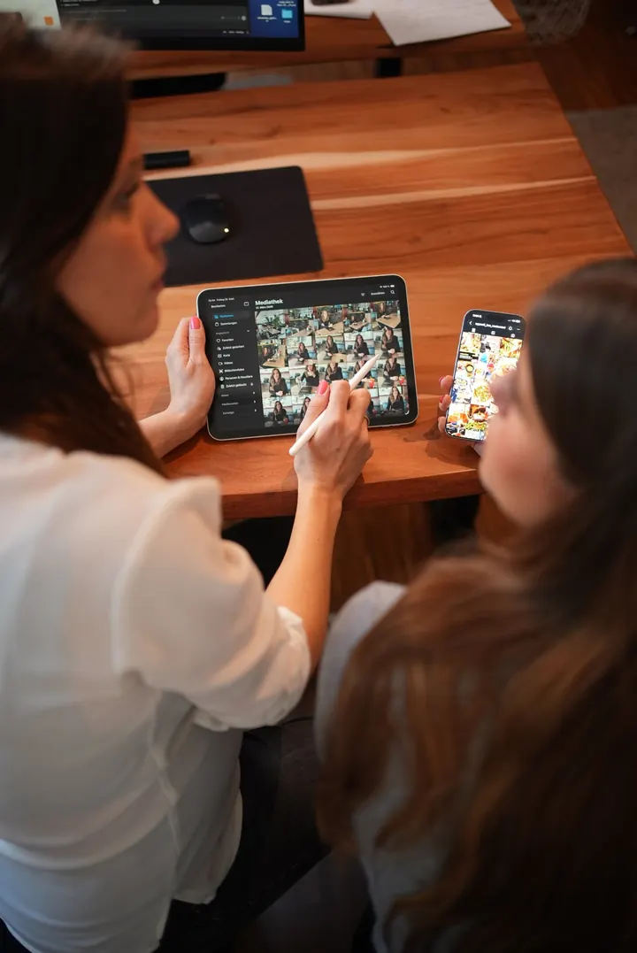 Unternehmensfotografie Hamburg: Zwei Kolleginnen besprechen Inhalte auf Tablet und Smartphone