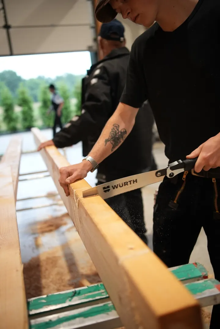 Businessfotografie Hamburg: Handwerker sägt einen Holzbalken in der Werkstatt
